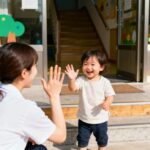 17개월 아기가 어린이집 앞에서 선생님과 인사하며 밝게 웃는 아침 등원 장면
